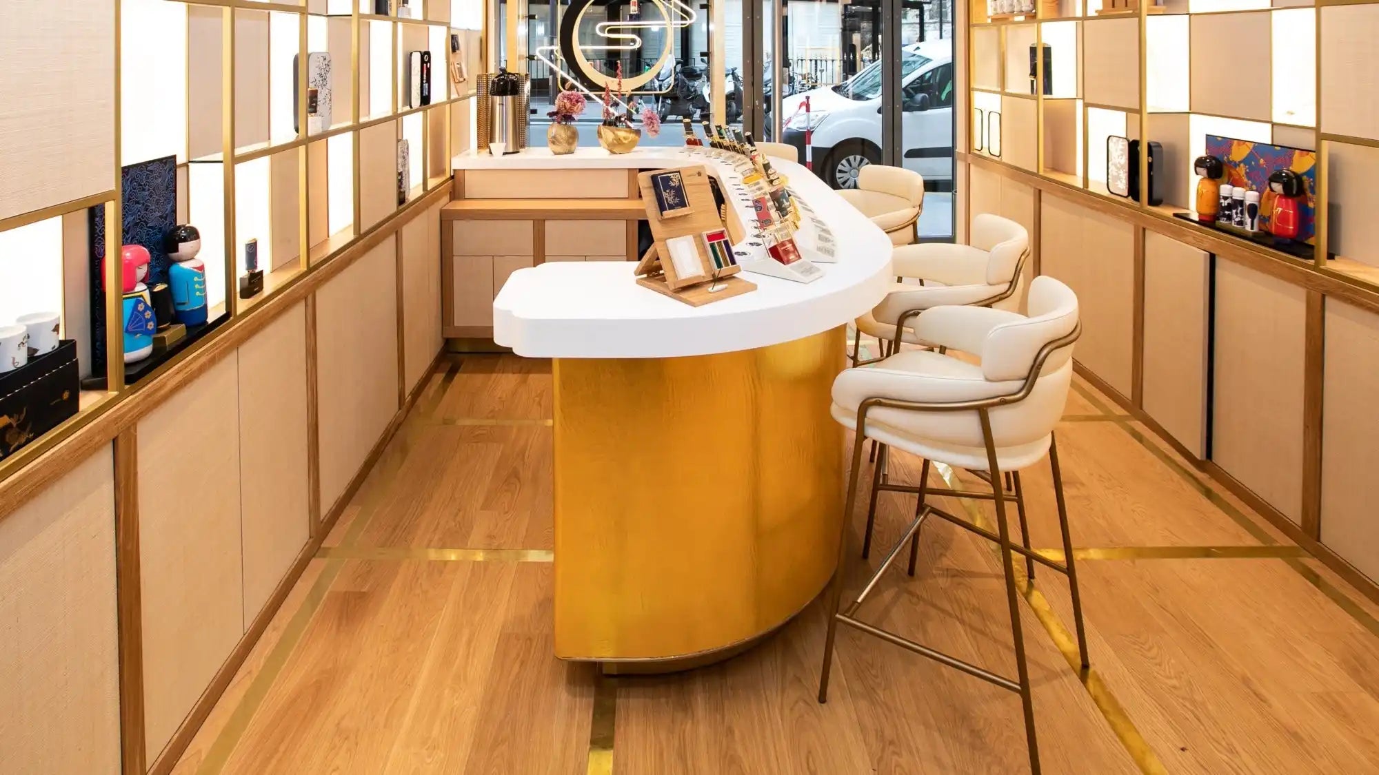 Curved golden reception counter with white top and beige bar stools.